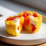 Two halves of an Easy 5-Minute Microwave Egg Caprese Cup showing runny yolk, white, and red tomatoes.