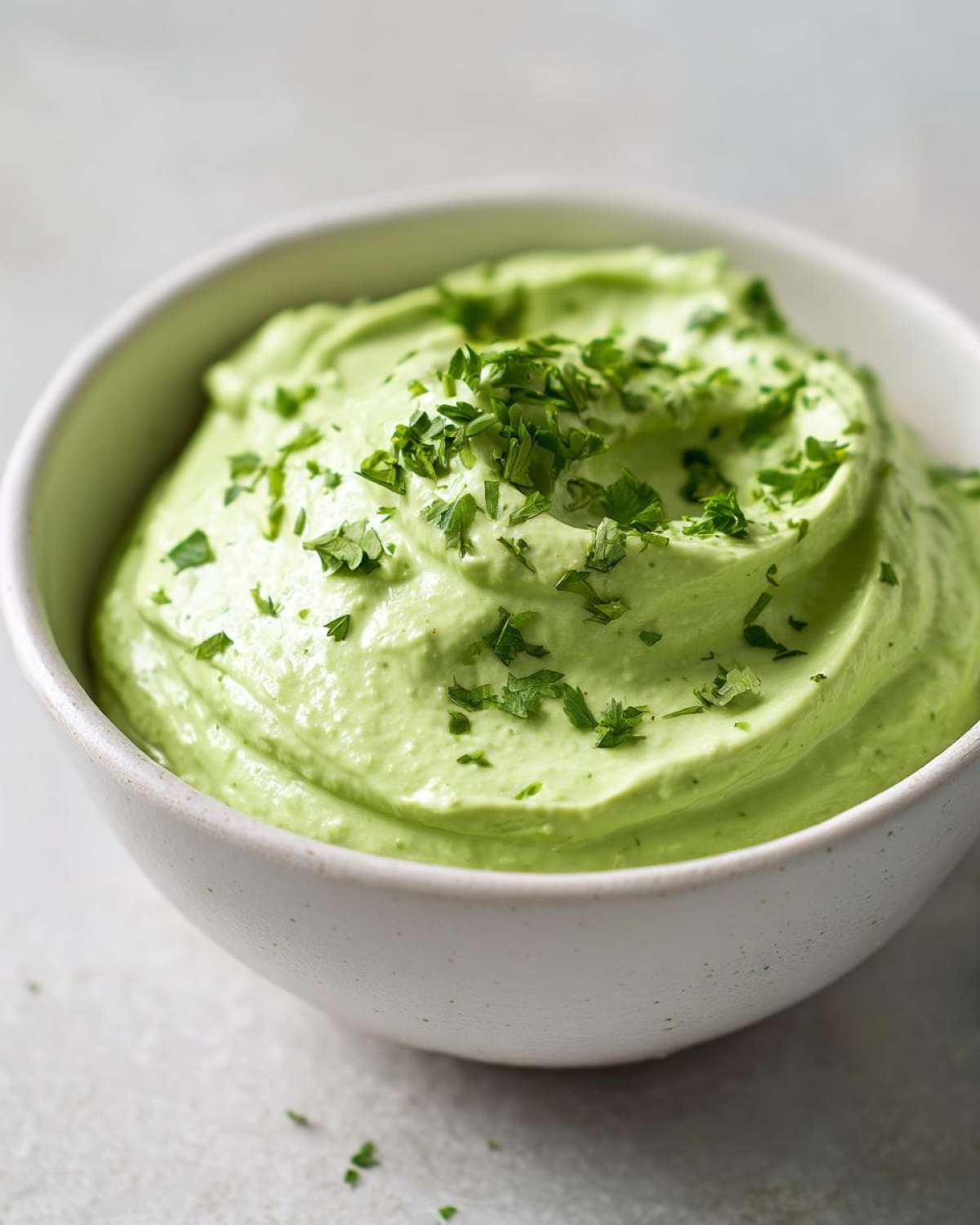 Close-up of a creamy, bright green Easy 5-Minute Salsa Verde Yogurt Dip topped with chopped fresh parsley.