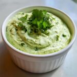 A close-up of creamy Easy 5-Minute Salsa Verde Yogurt Dip garnished with fresh cilantro in a white ramekin.