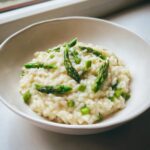 A close-up of creamy Easy Creamy Asparagus Risotto topped with bright green asparagus tips.