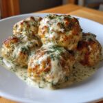 Five golden-brown Easy Creamy Greek Chicken Meatballs covered in a rich, creamy dill sauce.