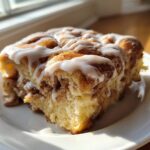 A close-up of a square serving of Easy Sheet Pan Cinnamon Roll Pancake Bake with thick white icing.