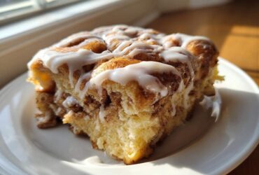 A close-up of a square serving of Easy Sheet Pan Cinnamon Roll Pancake Bake with thick white icing.
