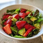 Close-up of a vibrant Easy Strawberry Avocado Salad featuring sliced strawberries, avocado chunks, and mixed greens.