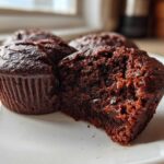 Close-up of a fudgy Brownie Muffin cut in half showing its moist interior and chocolate chips.