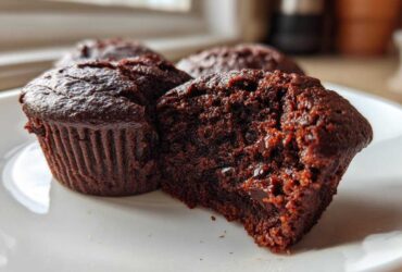Close-up of a fudgy Brownie Muffin cut in half showing its moist interior and chocolate chips.