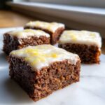 Four squares of moist Gingerbread Bars with Zesty Lemon Glaze topped with bright yellow zest.