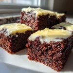 Four rich, dark squares of Gingerbread Bars with Zesty Lemon Glaze stacked on a white plate.