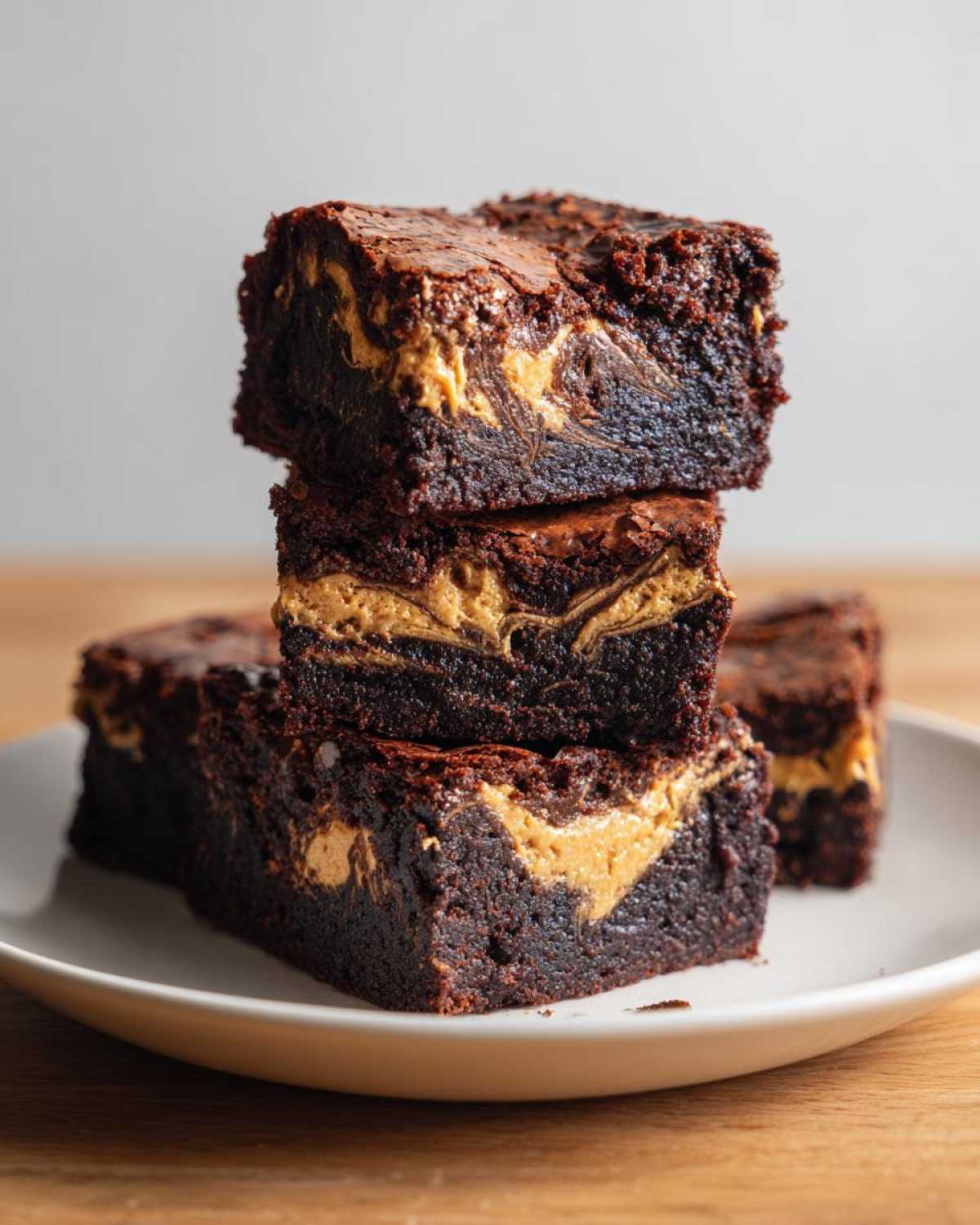 A stack of three fudgy Gluten-Free Chocolate Peanut Butter Swirl Brownies on a white plate.