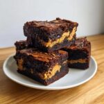 A stack of fudgy Gluten-Free Chocolate Peanut Butter Swirl Brownies on a white plate.