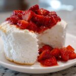 Close-up of a slice of fluffy Gluten-Free Lemon Strawberry Angel Food Cup topped with macerated strawberries.