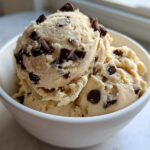 Three scoops of creamy Greek Yogurt Cookie Dough studded with mini chocolate chips served in a white bowl.