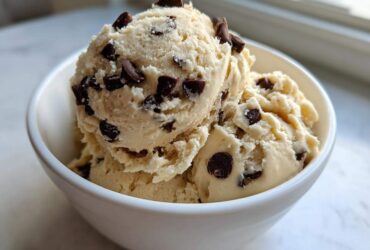 Three scoops of creamy Greek Yogurt Cookie Dough studded with mini chocolate chips served in a white bowl.