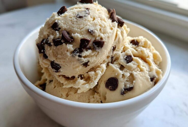 Three scoops of creamy Greek Yogurt Cookie Dough studded with mini chocolate chips served in a white bowl.