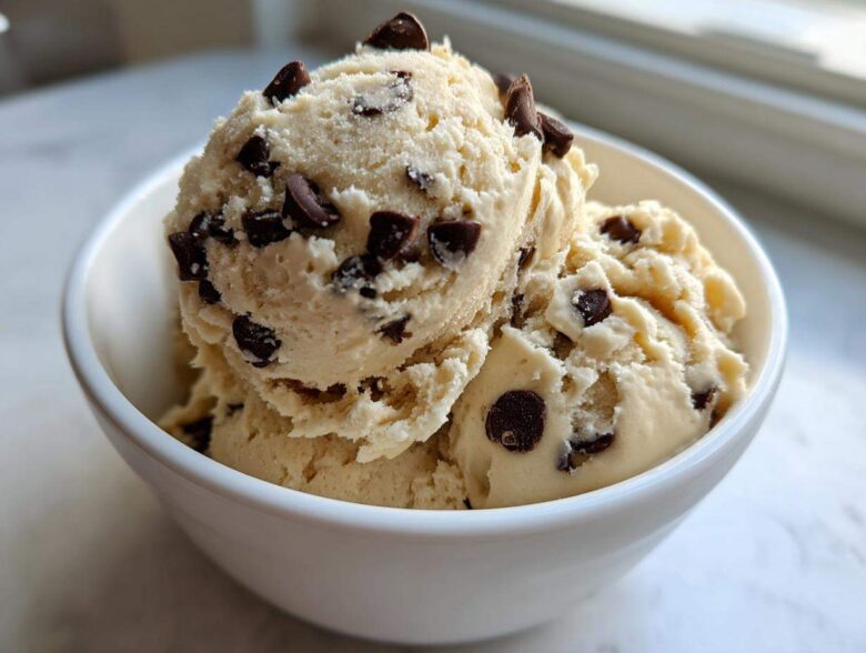 Three scoops of creamy Greek Yogurt Cookie Dough studded with mini chocolate chips served in a white bowl.