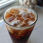 Close-up of Iced Brown Sugar Cinnamon Cold Brew with ice, creamy foam, and a dusting of cinnamon.
