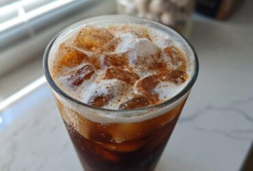 Close-up of Iced Brown Sugar Cinnamon Cold Brew with ice, creamy foam, and a dusting of cinnamon.