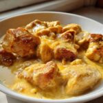 Close-up of tender chicken pieces coated in rich, yellow Instant Pot Creamy Coconut Chicken Curry sauce in a white bowl.