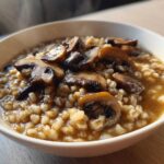 Close-up of Instant Pot Creamy Mushroom Barley Soup topped with sautéed brown mushrooms in a white bowl.