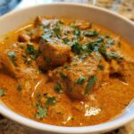 Close-up of rich, orange-hued Keto Creamy Butter Chicken Skillet topped with fresh cilantro.