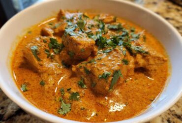 Close-up of rich, orange-hued Keto Creamy Butter Chicken Skillet topped with fresh cilantro.