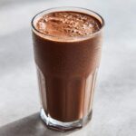 A tall, sweating glass filled with a thick, cold Keto Creamy Chocolate Peanut Butter Shake.