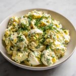 A close-up of a bowl filled with Keto Creamy Herb Deviled Egg Salad, topped with fresh dill.
