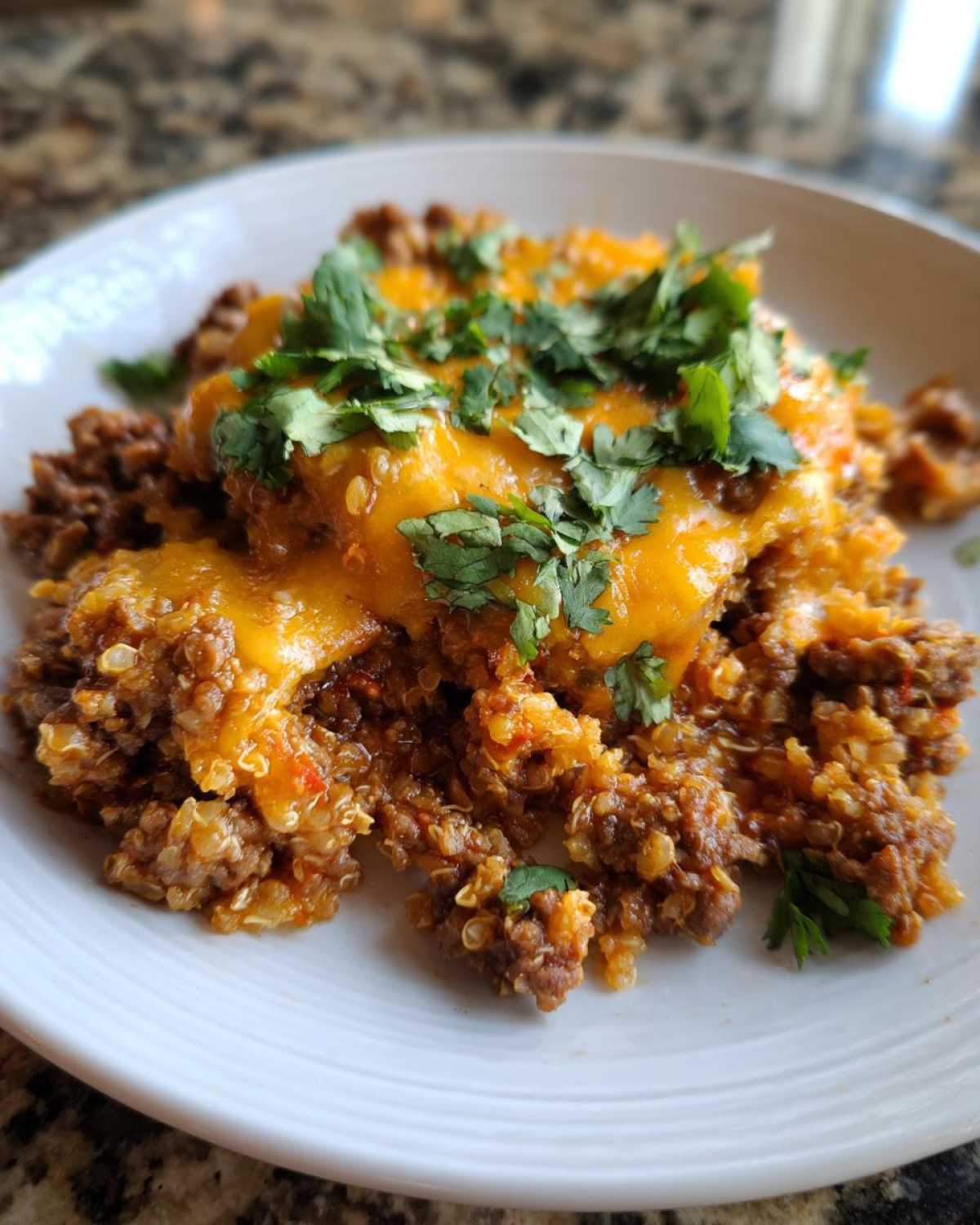 A close-up of a serving of Keto Creamy Taco Skillet with cauliflower rice, topped with melted cheddar cheese and fresh cilantro.