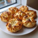 Six golden brown Keto Everything Bagel Cloud Bread Bites topped with poppy seeds arranged on a white plate.