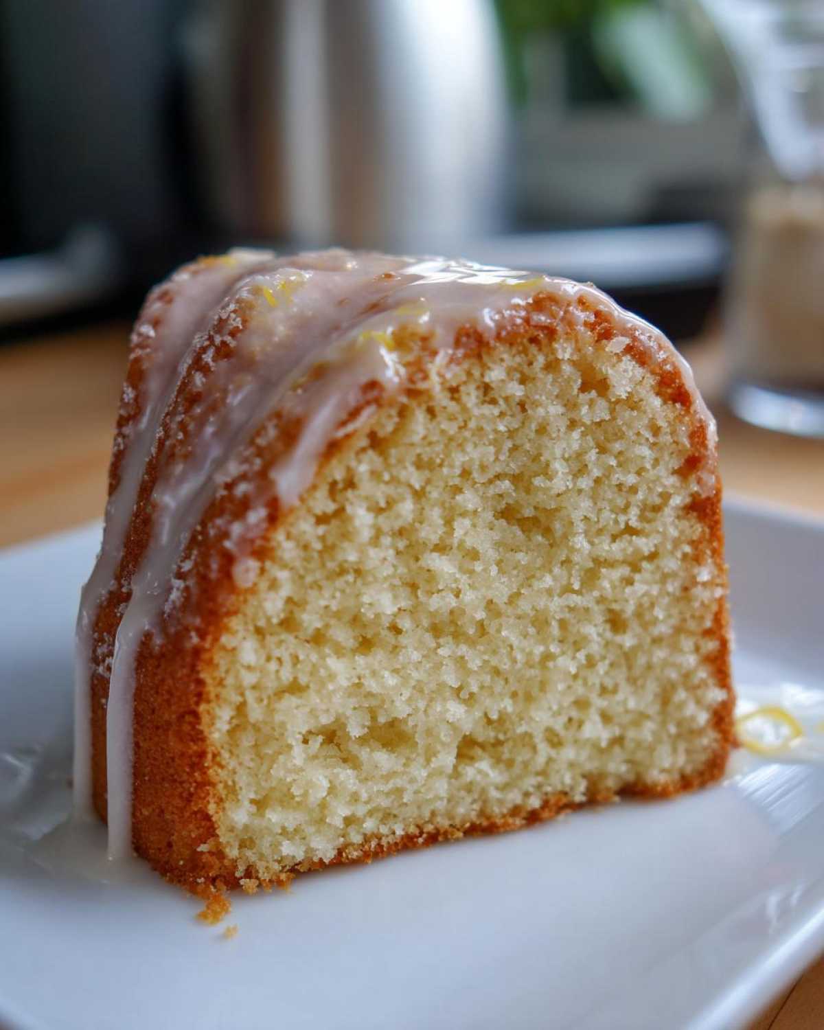 Close-up of a slice of moist London Fog Cake showing the crumb texture and white glaze topping.