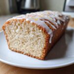 Close-up of a slice of moist London Fog Cake with a white glaze drizzled over the top.