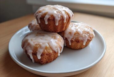 Four golden Mini Lemon Cakes Lavender Glaze stacked slightly on a light gray plate.