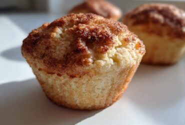Close-up of a moist Apple Cinnamon Muffin featuring a rich cinnamon sugar crust.