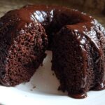A slice removed from a rich, dark Chocolate Bundt Cake covered in glossy chocolate glaze.