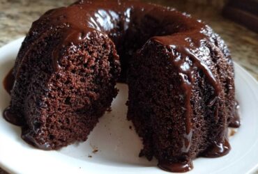 A slice removed from a rich, dark Chocolate Bundt Cake covered in glossy chocolate glaze.