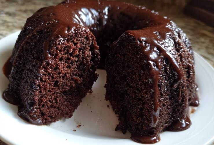 A slice removed from a rich, dark Chocolate Bundt Cake covered in glossy chocolate glaze.