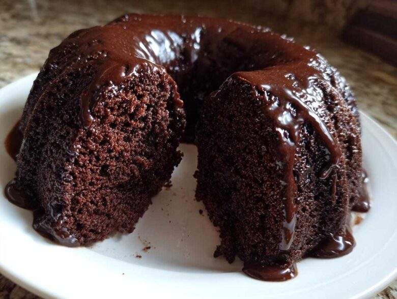 A slice removed from a rich, dark Chocolate Bundt Cake covered in glossy chocolate glaze.