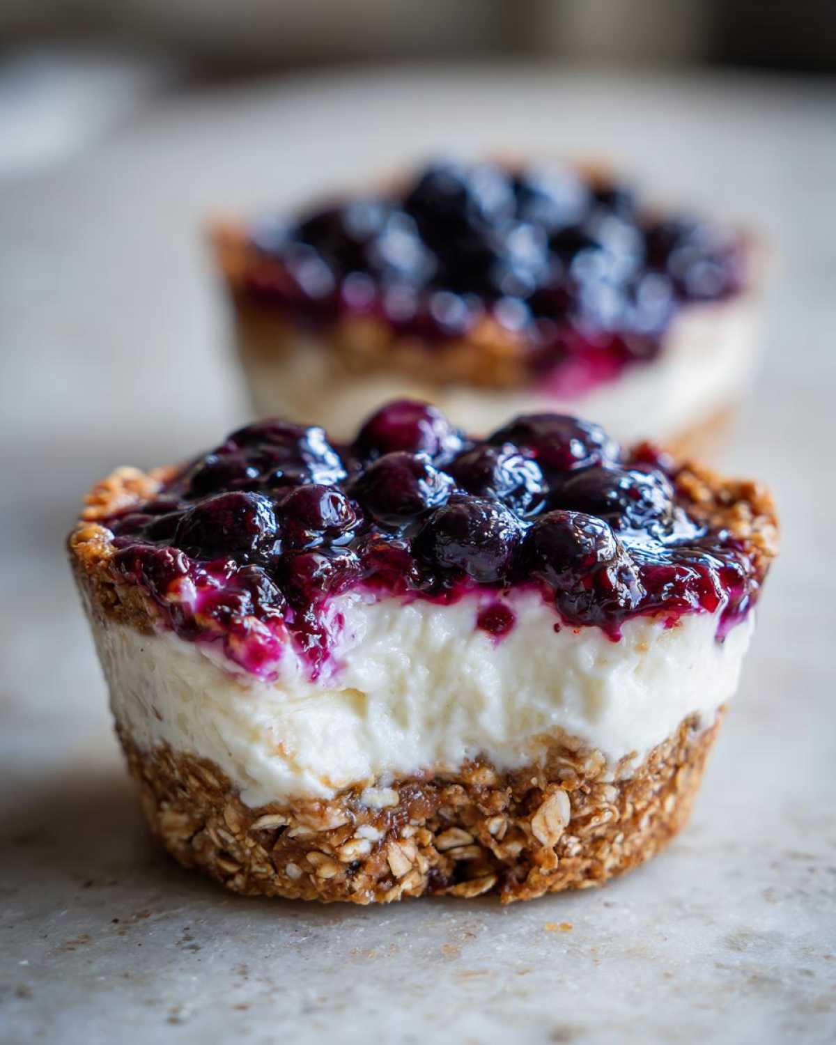 Close-up of a No-Bake Blueberry Cheesecake Oat Cup showing the oat crust, creamy filling, and blueberry topping.