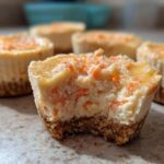 Close-up of a bitten No-Bake Carrot Cake Cheesecake Cup showing the creamy filling and graham cracker crust.