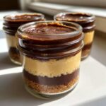 Three layered No-Bake Chocolate Peanut Butter Pie Jars featuring crust, peanut butter filling, and chocolate topping.