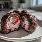 A No-Bake Chocolate Strawberry Yogurt Cluster cut in half showing the yogurt filling and strawberry slice inside.