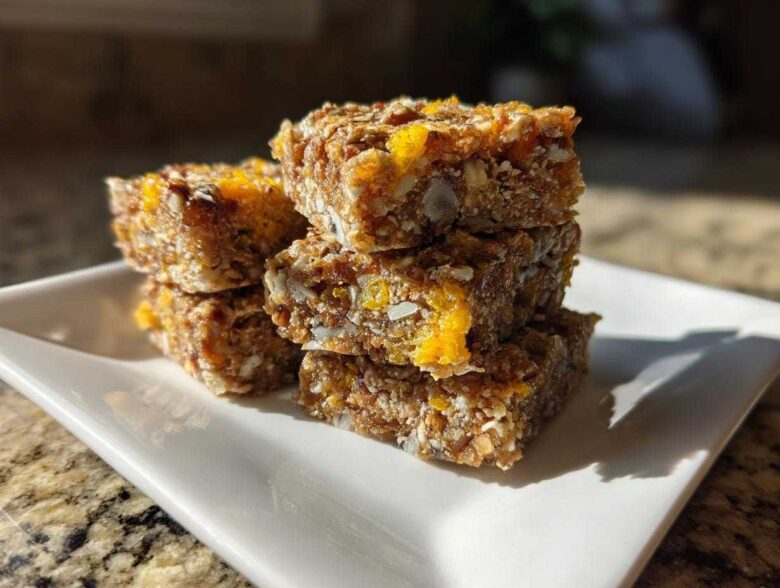 A stack of four No-Bake Lemon Almond Date Bars featuring visible oats, almonds, and bright yellow lemon zest.