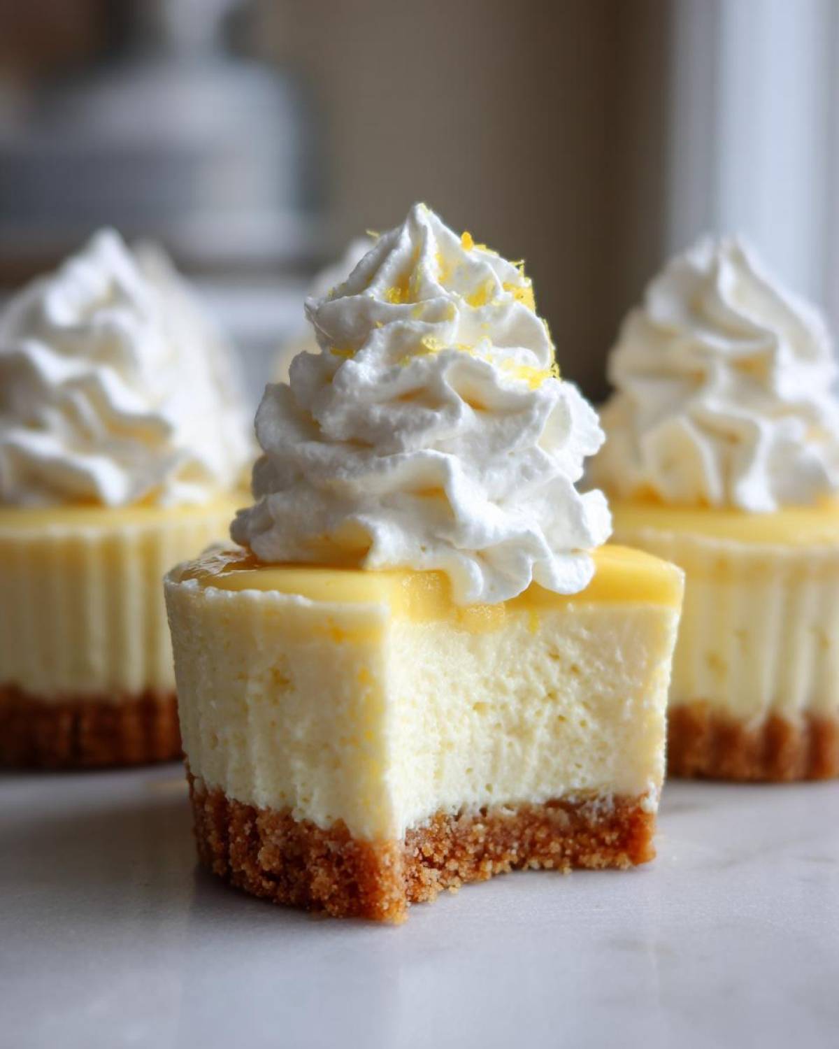 Close-up of a No-Bake Lemon Cream Pie Cup cut in half, showing the graham cracker crust, creamy filling, and whipped topping.