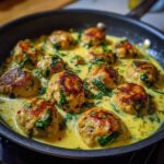 Close-up of browned One-Pan Creamy Lemon Garlic Turkey Meatballs simmering in a rich, yellow cream sauce with spinach.