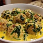 Close-up of One-Pan Creamy Lemon Garlic Turkey Meatballs served in a white bowl with spinach and a rich yellow sauce.