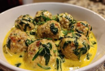 Close-up of One-Pan Creamy Lemon Garlic Turkey Meatballs served in a white bowl with spinach and a rich yellow sauce.