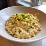 A close-up of One-Pot Creamy Lemon Garlic Farro served in a white bowl, topped with lemon zest and parsley.
