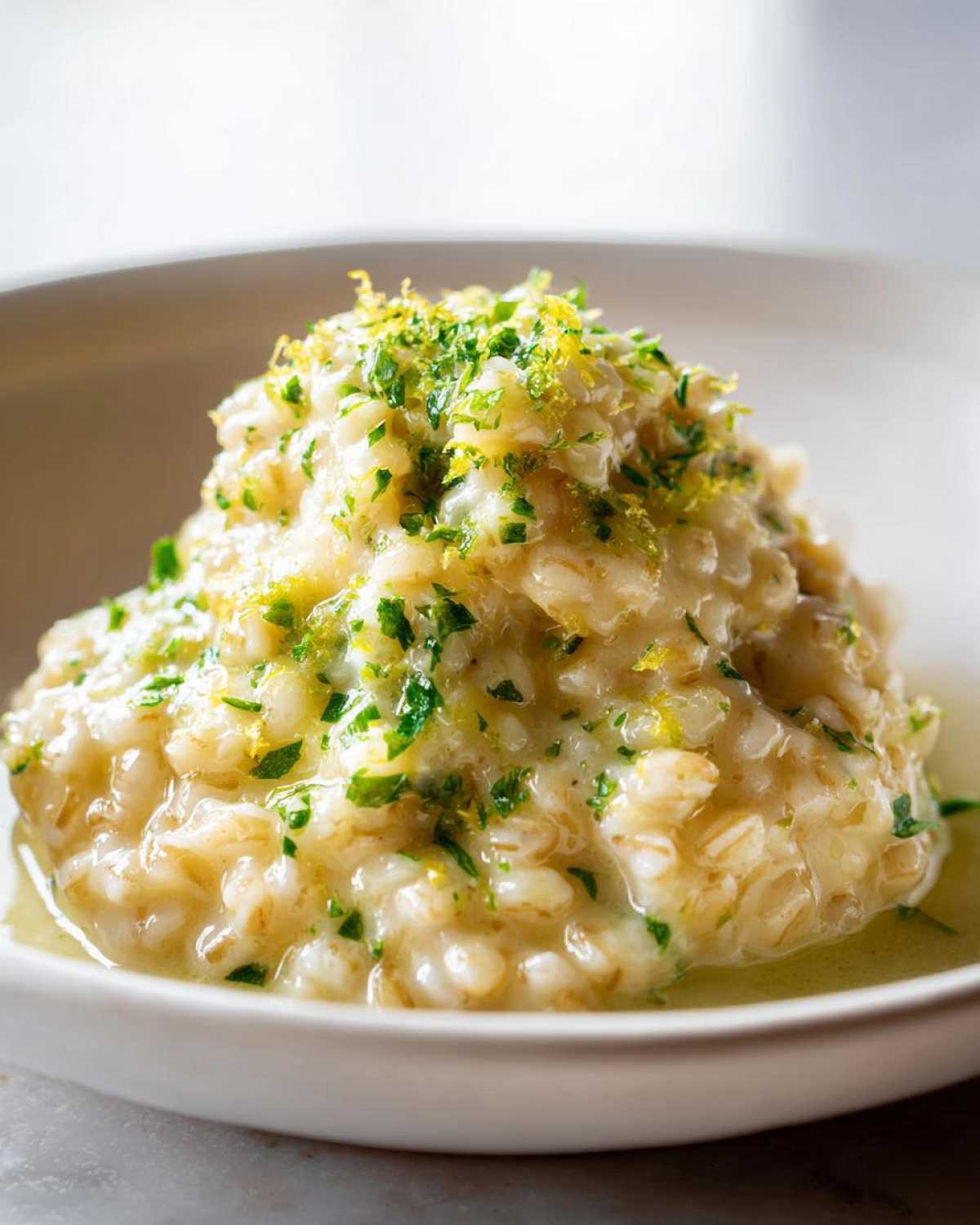 Close-up of a creamy serving of One-Pot Creamy Lemon Garlic Farro topped with fresh parsley and lemon zest.
