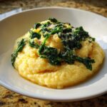 A serving of One-Pot Creamy Spinach Parmesan Polenta topped with wilted spinach and grated cheese.