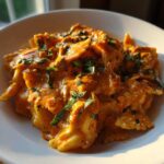 Close-up of One-Pot Creamy Tomato Basil Tortilla Pasta featuring farfalle pasta coated in a rich, orange sauce and topped with fresh basil.